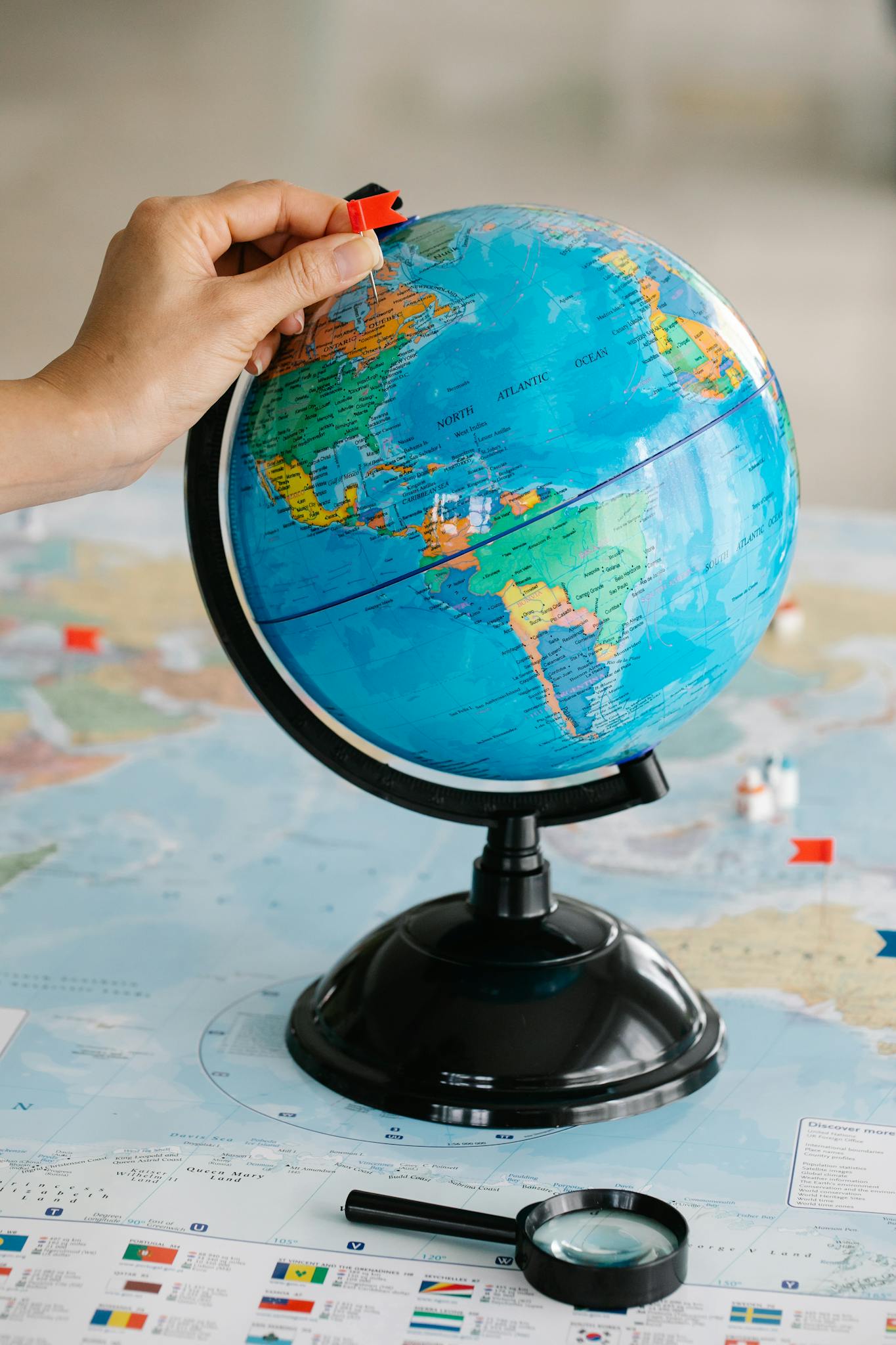 Close-up of a hand adding a pin to a globe, symbolizing travel planning and exploration.